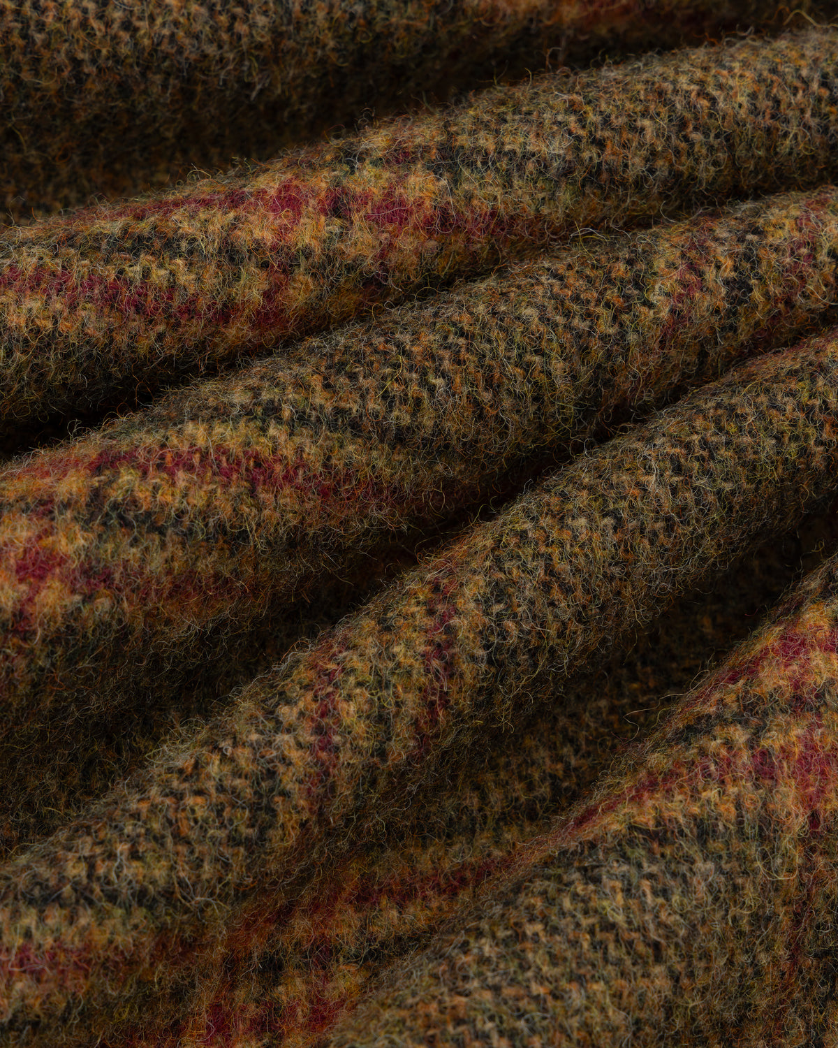 Close-up of brown, green, and red Plaid Tweed Suit Trouser fabric folded into ridges.