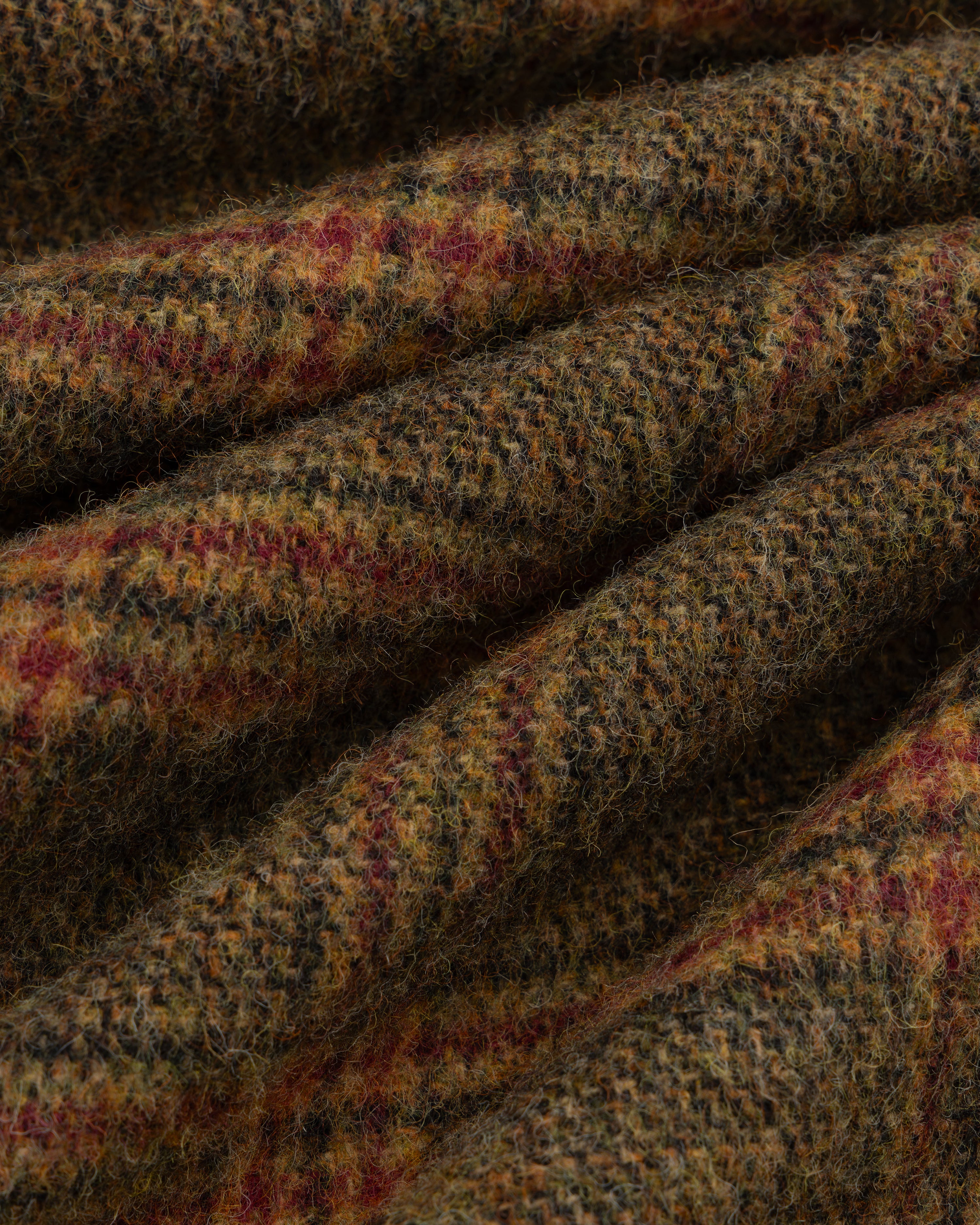 Close-up of brown, green, and red Plaid Tweed Suit Trouser fabric folded into ridges.