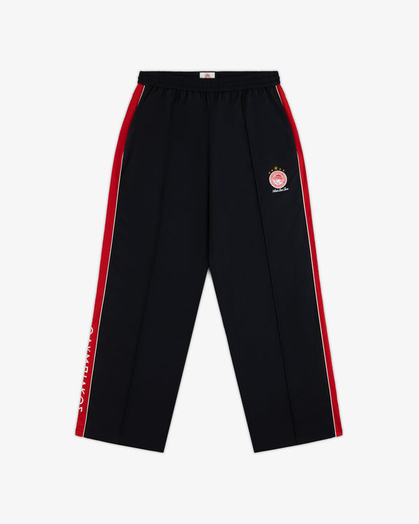 ALD / Olympiacos F.C. Nylon Track Pant in black with red and white side stripes and a soccer team crest on the hip.