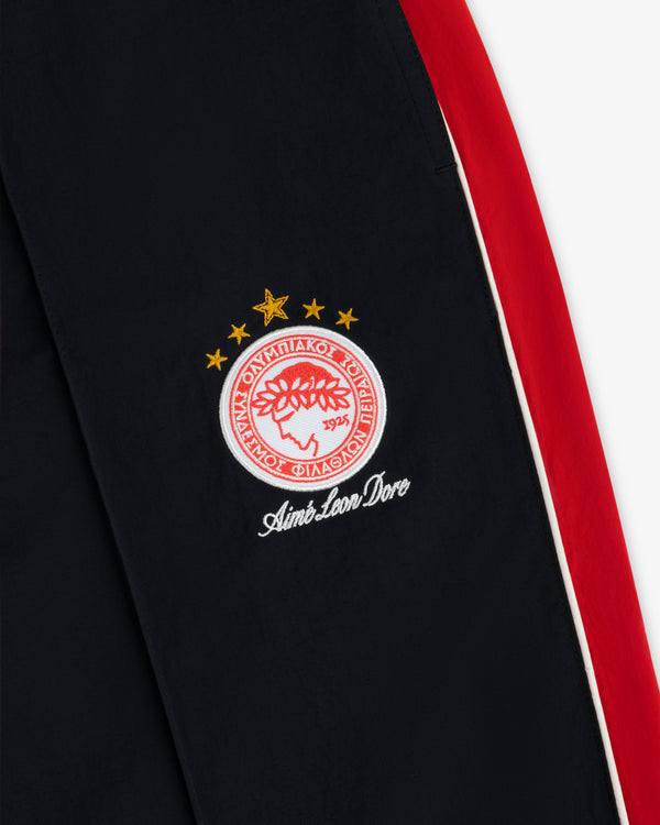 ALD / Olympiacos F.C. Nylon Track Pant in black with red and white side stripes and an embroidered club crest.