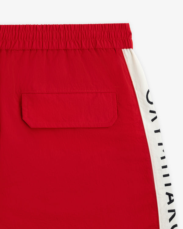ALD / Olympiacos F.C. Nylon Training Short: red nylon shorts with an elastic waistband, back pocket, and striped text side.