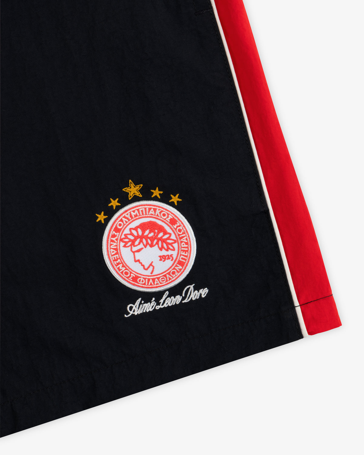 ALD / Olympiacos F.C. Nylon Training Short: black shorts with a red side stripe and a red and white crest with three stars.