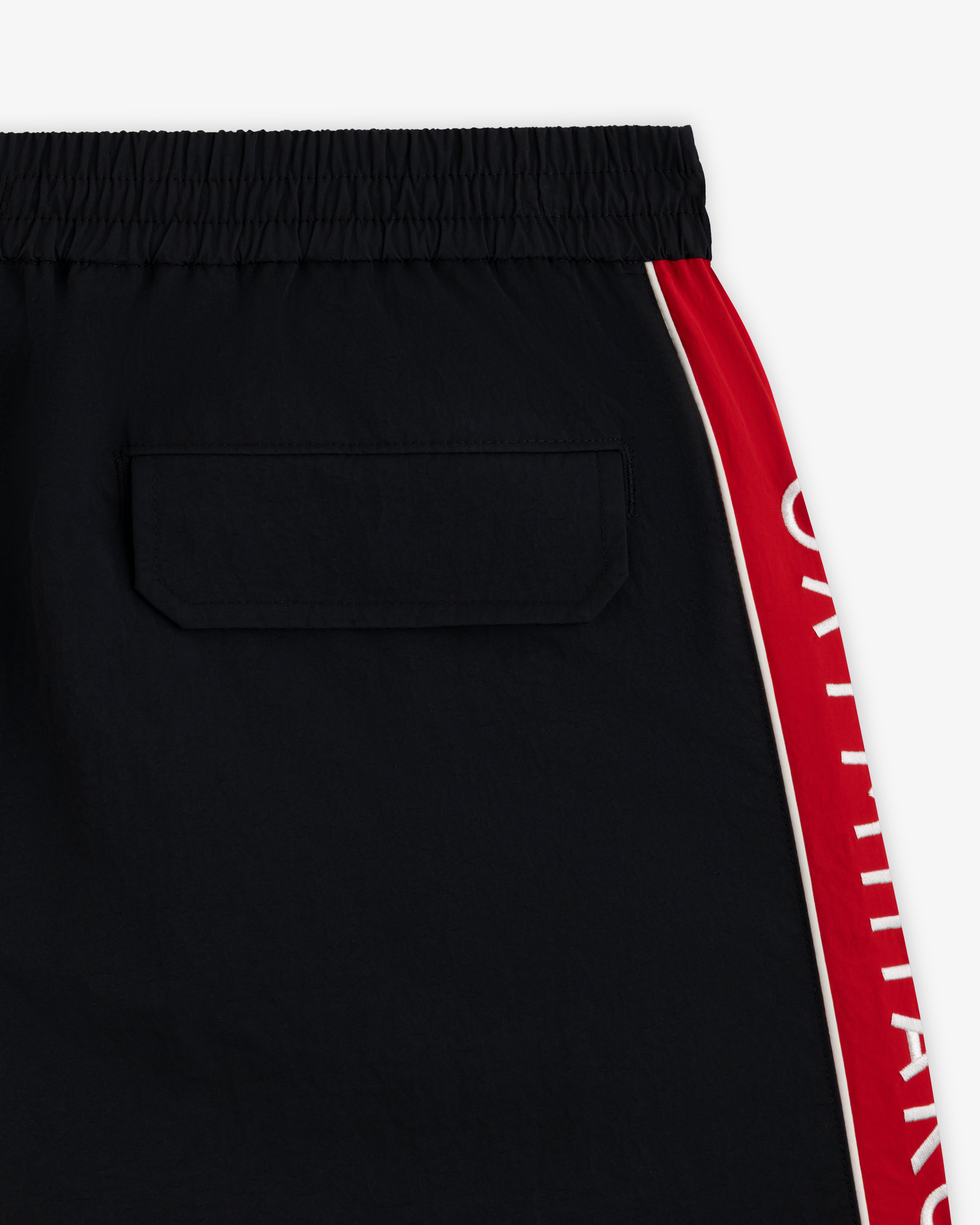 ALD / Olympiacos F.C. Nylon Training Short: black nylon shorts with a back pocket and a red side stripe with white lettering.