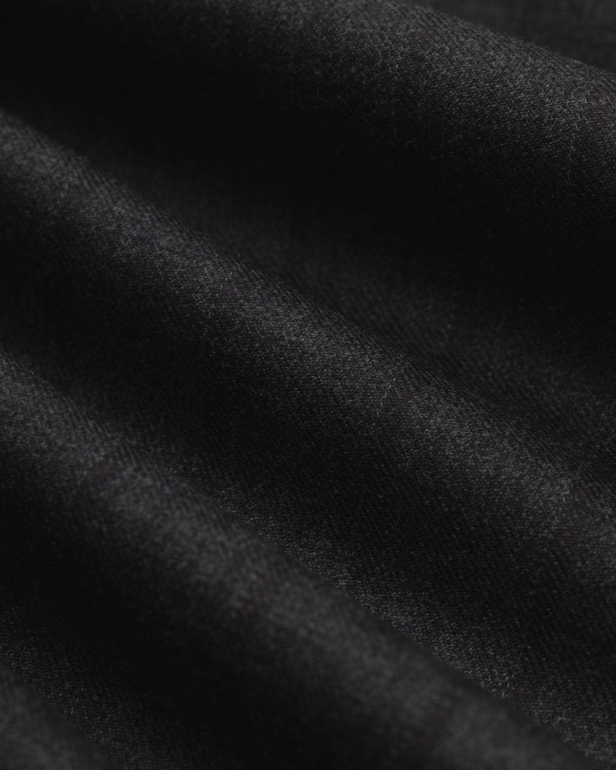 Close-up of black fabric with subtle vertical pinstripes and soft folds on a Striped Tailored Maxi Skirt.