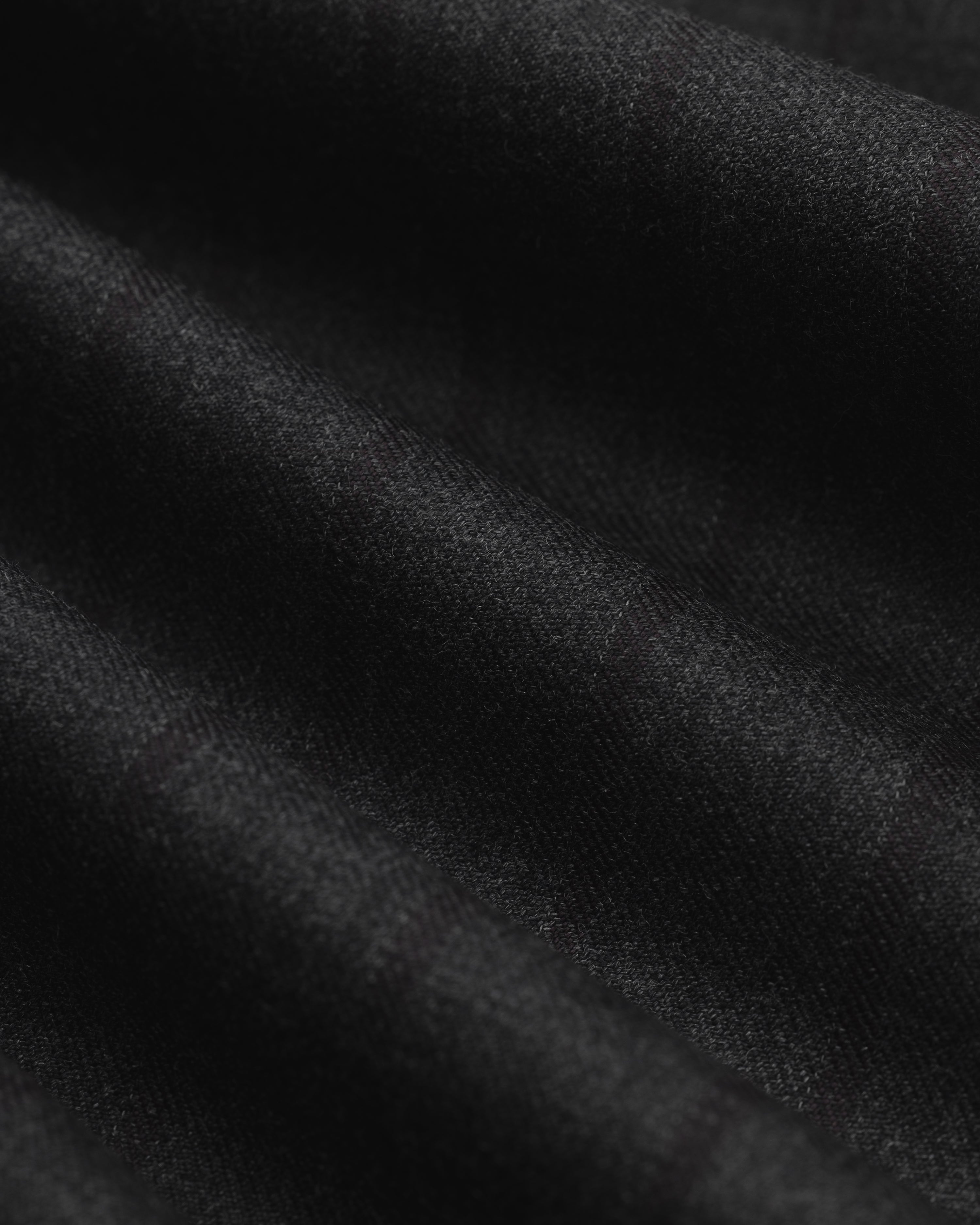 Close-up of black fabric with subtle vertical pinstripes and soft folds on a Striped Tailored Maxi Skirt.