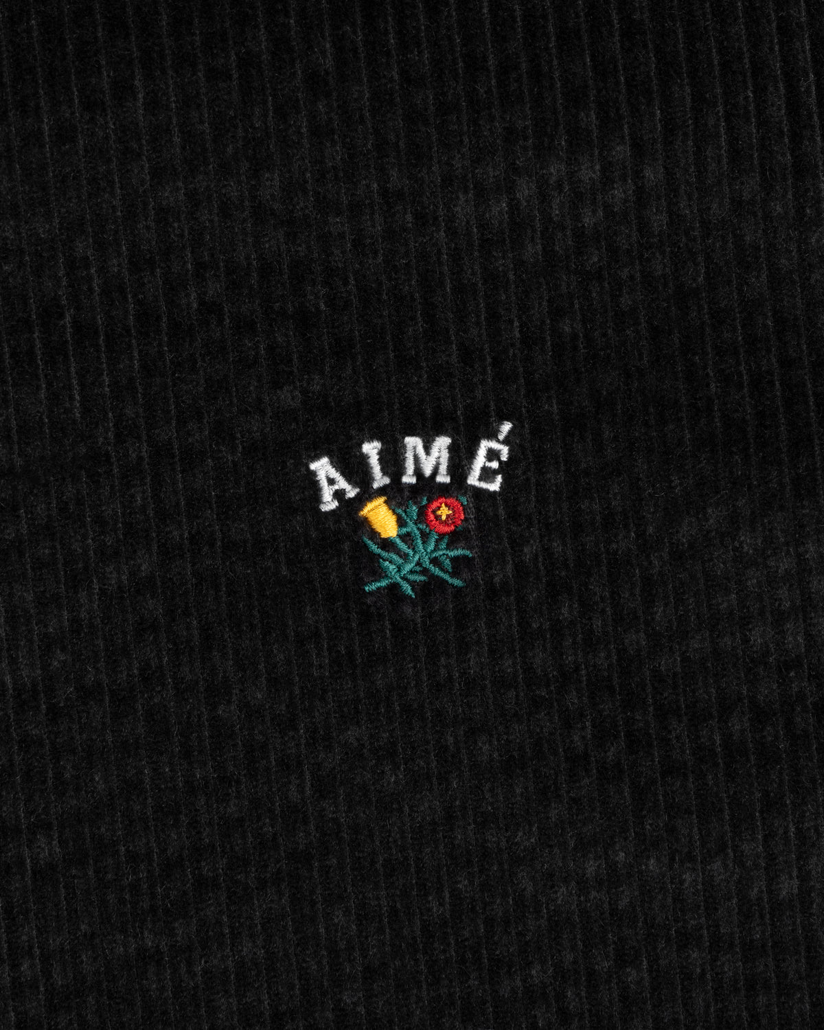 Black corduroy Corduroy Leon Overshirt fabric embroidered with the word AIMÉ above a flower.