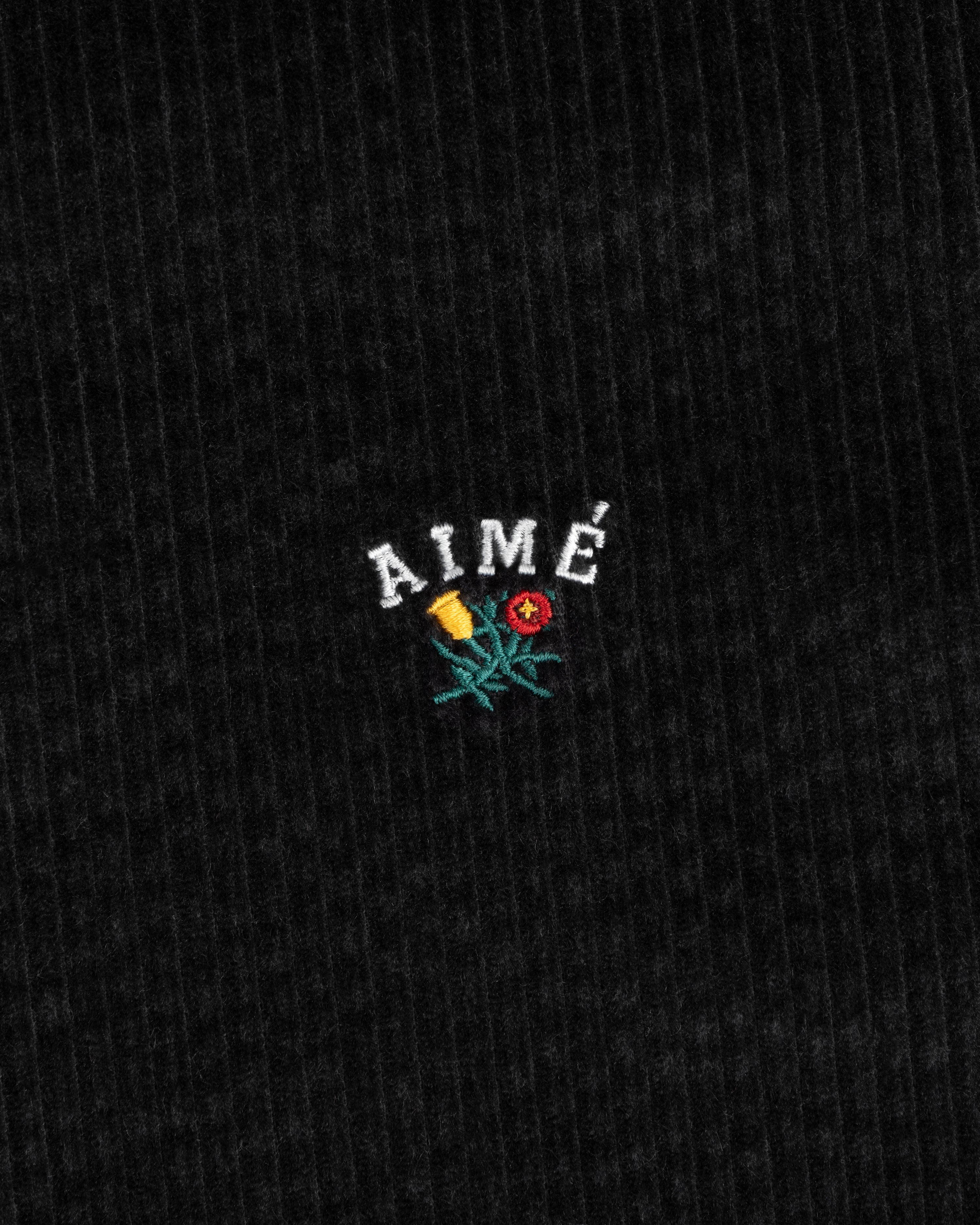 Black corduroy Corduroy Leon Overshirt fabric embroidered with the word AIMÉ above a flower.