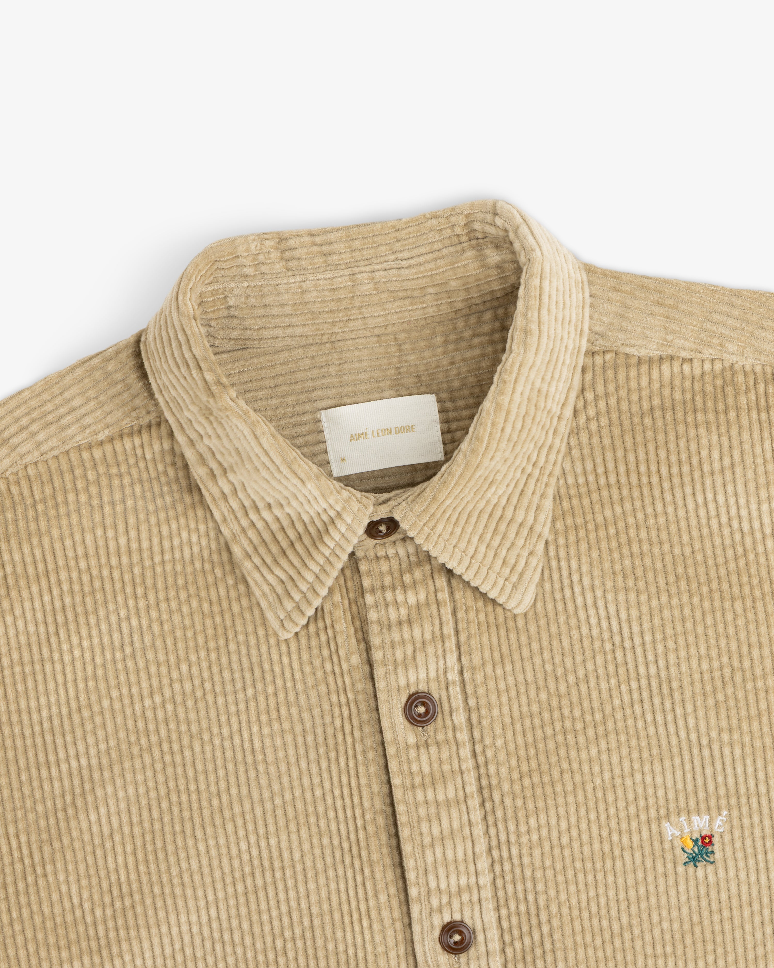 Tan Corduroy Leon Overshirt with a button-down front and a small floral logo on the chest.