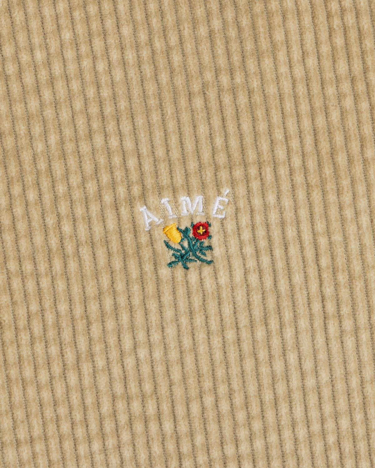 Tan Corduroy Leon Overshirt featuring an embroidered yellow and red flower with the text AIMÉ arched above it.