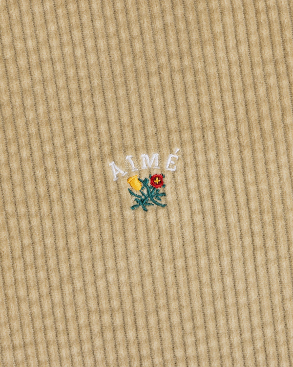 Tan Corduroy Leon Overshirt featuring an embroidered yellow and red flower with the text AIMÉ arched above it.
