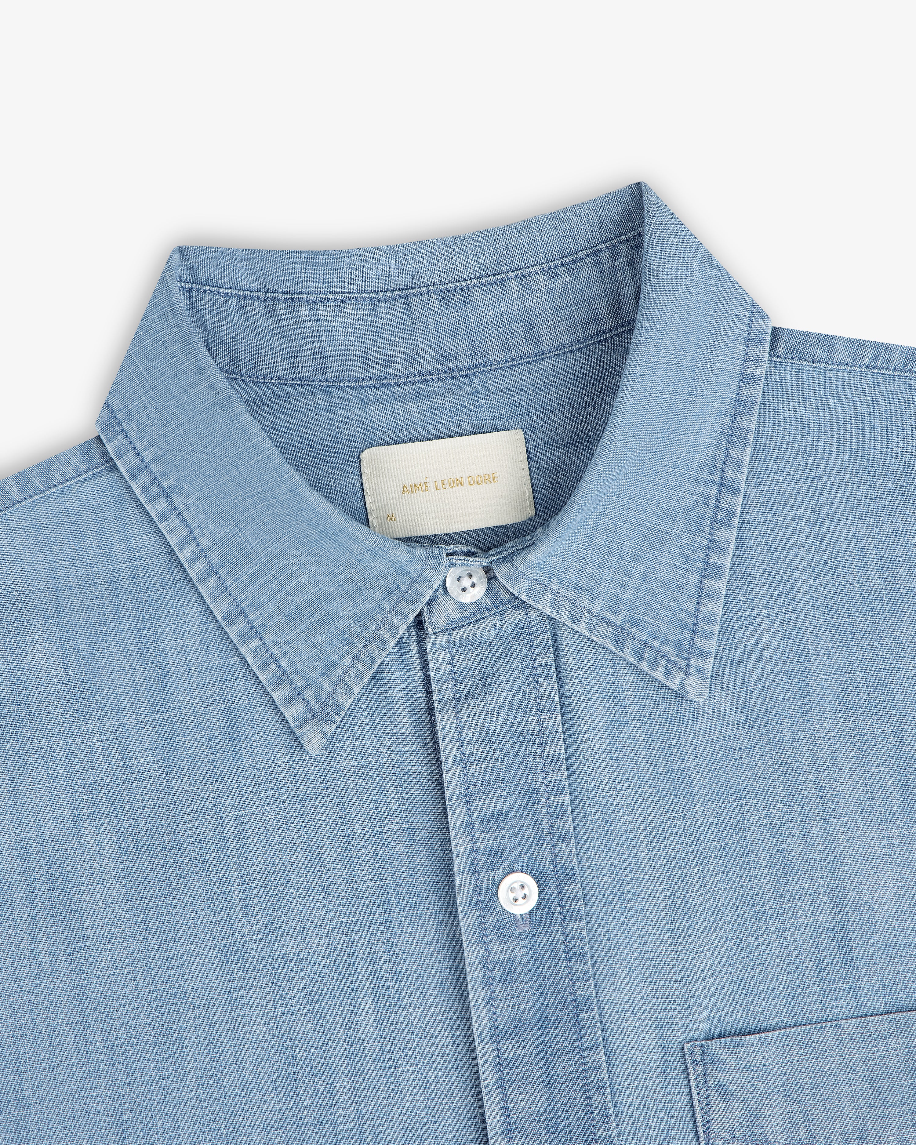 Bayard Chambray Shirt: light blue denim, pointed collar, white buttons, chest pocket; shown on white background.