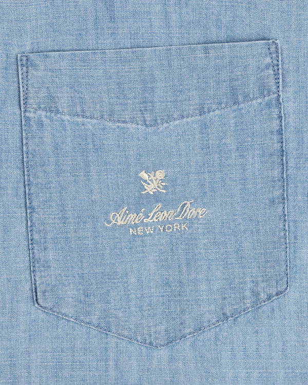 Bayard Chambray Shirt: Light blue pocket with white “Aimé Leon Dore NEW YORK” embroidery and a flower logo above.