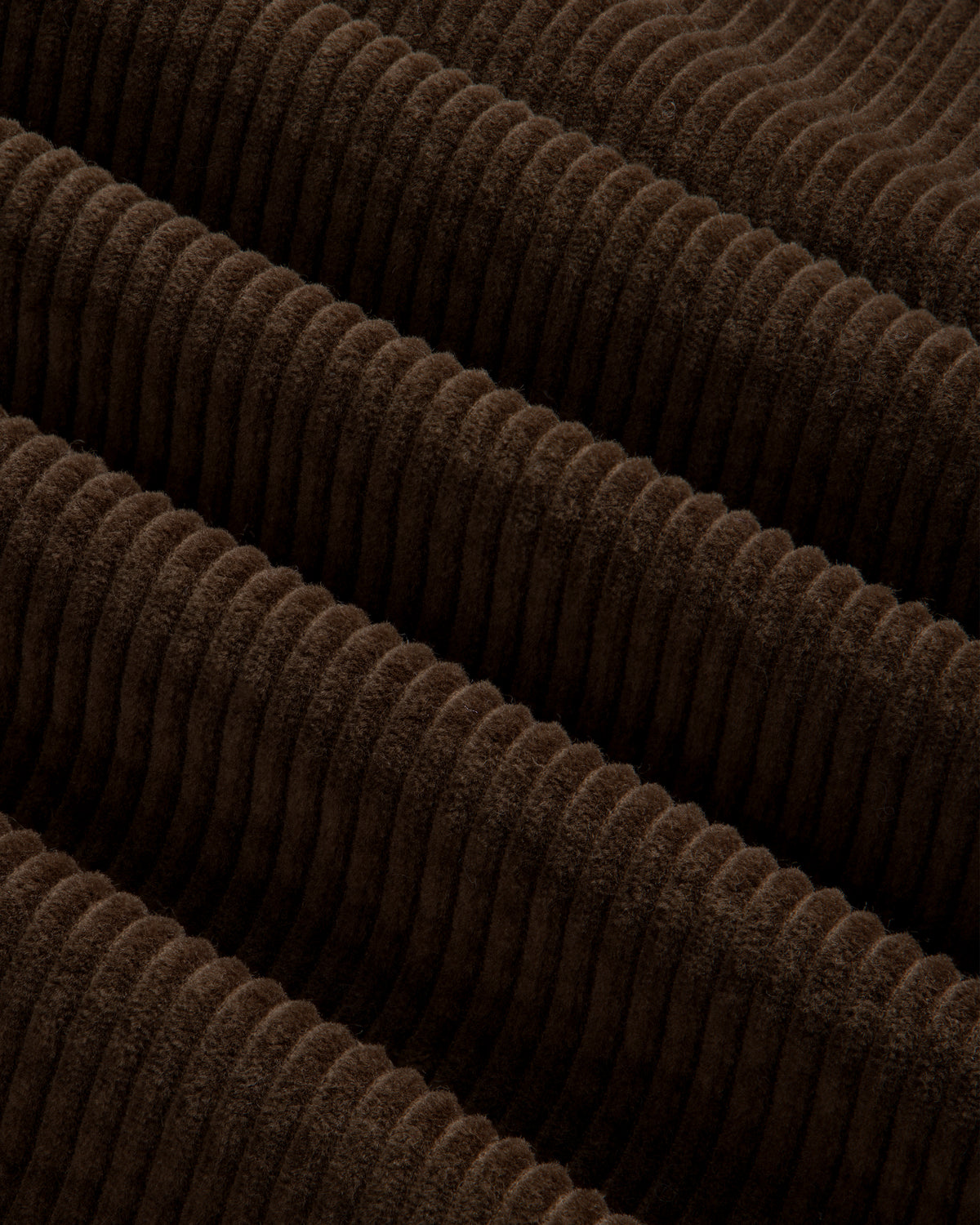 Close-up of brown corduroy fabric with wide, vertical ribs on a Quarter Zip Corduroy Shirt.