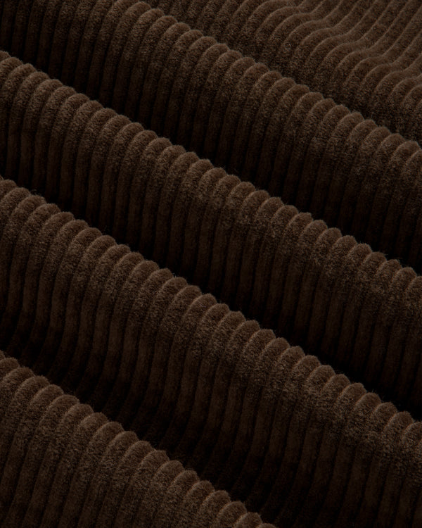 Close-up of brown corduroy fabric with wide, vertical ribs on a Quarter Zip Corduroy Shirt.
