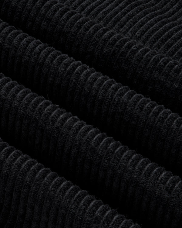 Close-up of black corduroy fabric on a Quarter Zip Corduroy Shirt with thick, diagonal ridges.