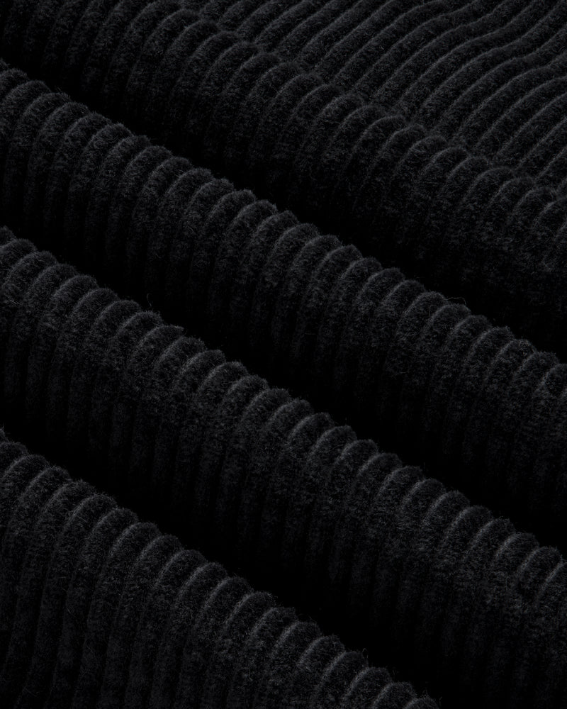 Close-up of black corduroy fabric on a Quarter Zip Corduroy Shirt with thick, diagonal ridges.