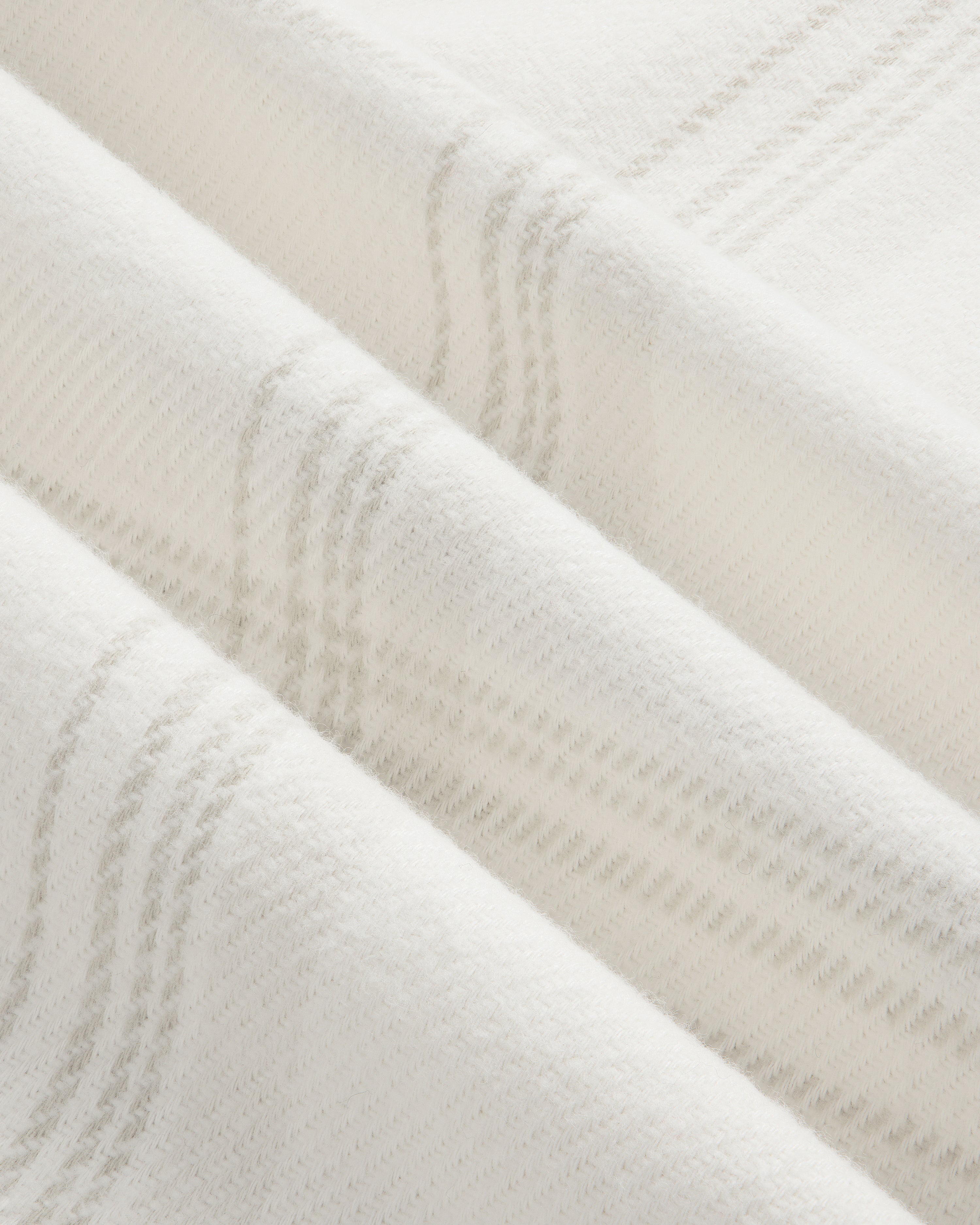 Close-up of a Yarn Dyed Plaid Overshirt in white fabric with a subtle, pale gray plaid pattern.