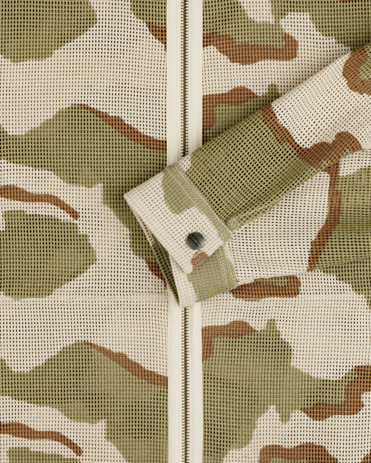Camo Mesh Zip Overshirt in a tan, olive, and brown camouflage mesh fabric with a buttoned sleeve cuff.