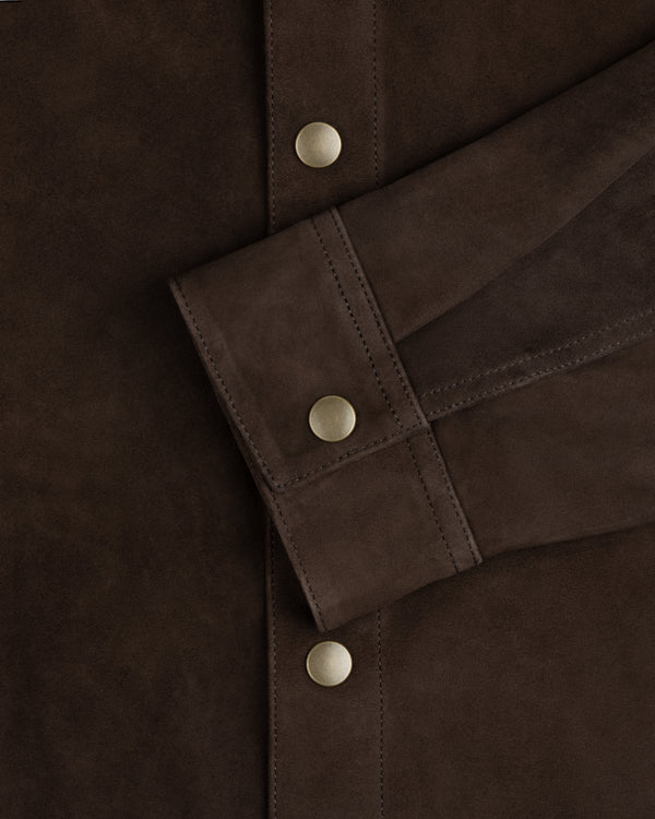 Dark brown suede cuff of the Suede Overshirt with a matte gold snap button.