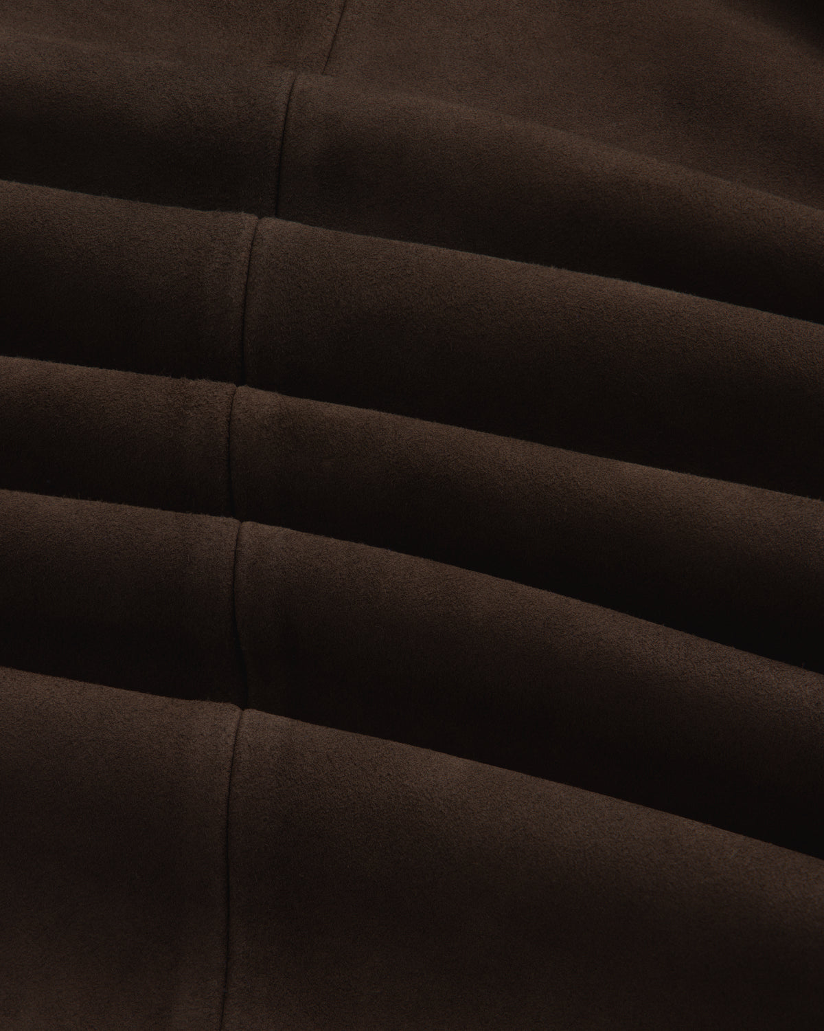Close-up of the dark brown Suede Overshirt showing its fabric texture, seams, and folds.
