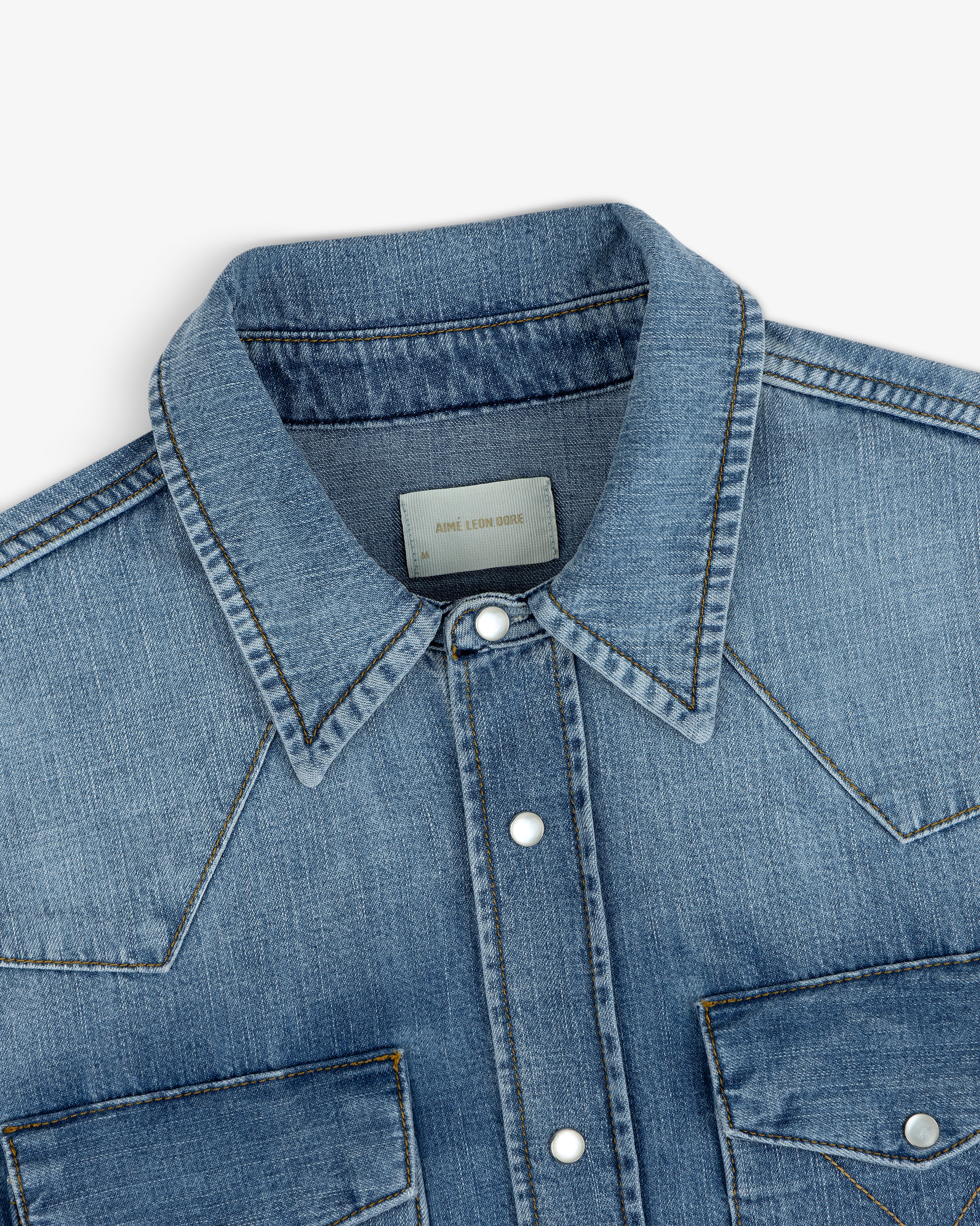 Close-up of a blue Denim Western Shirt featuring a pointed collar, snap buttons, and western-style shoulder yokes.