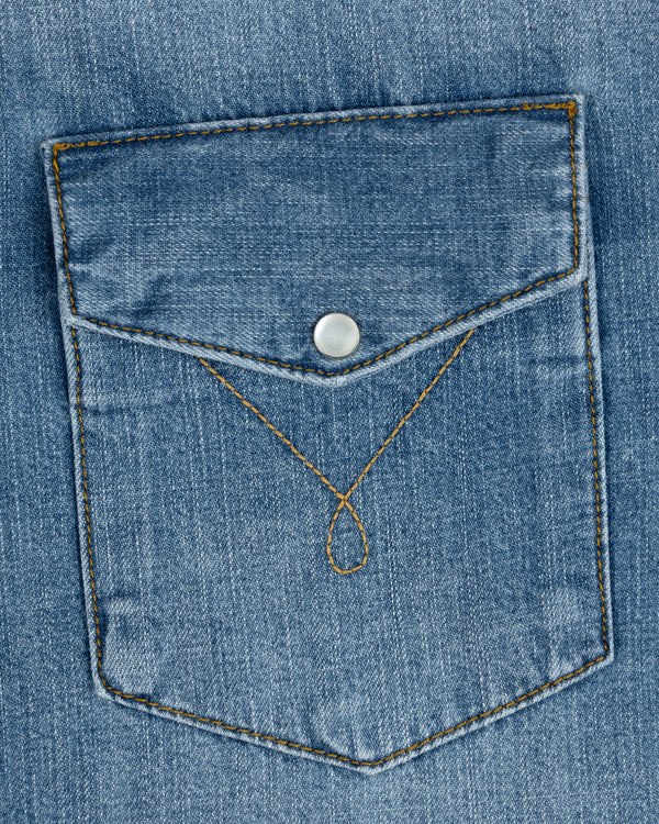 A Denim Western Shirt pocket with a pointed flap, silver snap button, and decorative gold stitching.