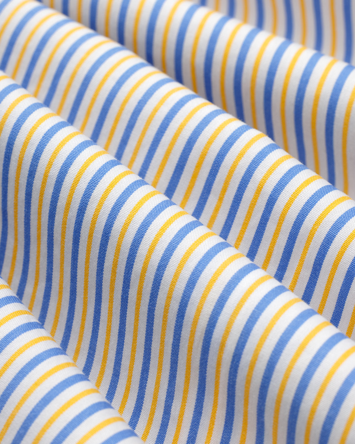 Striped Button Down Poplin Shirt fabric with vertical blue and yellow stripes folded in soft, deep waves.