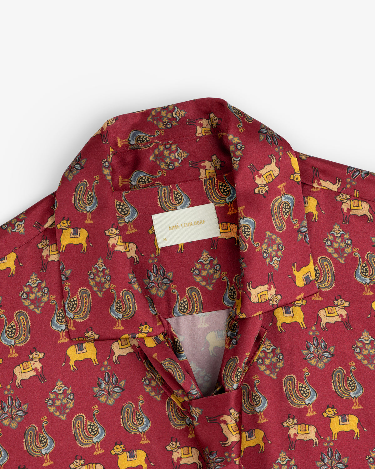 Archival Print Silk Tie Neck Blouse in burgundy with a stylized animal and floral print and a collared neckline.