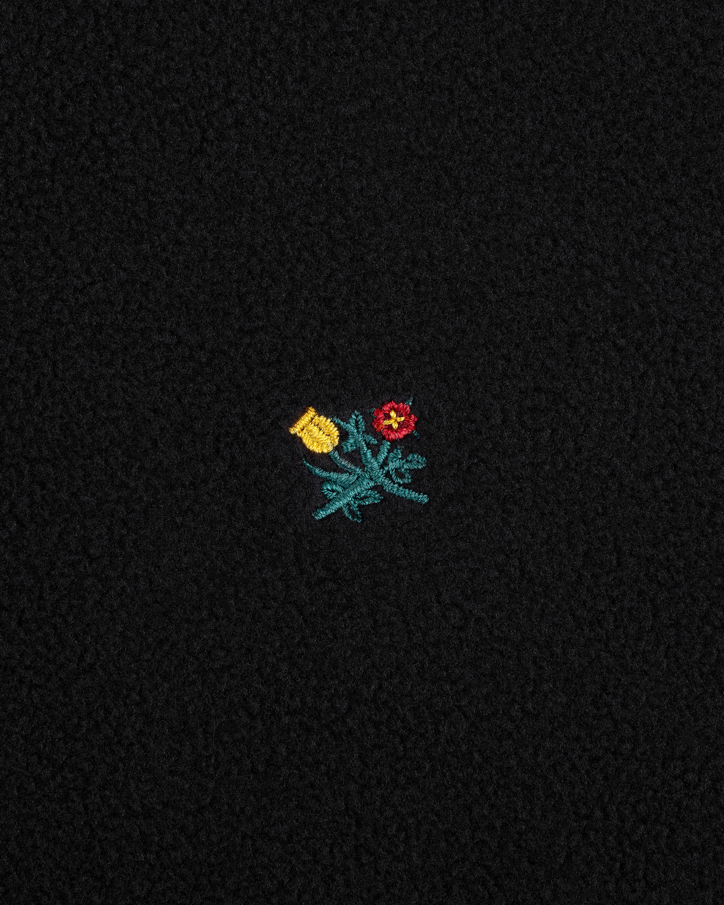 Crest Long-Sleeve Fleece Tee in black fleece with a small yellow and red floral embroidery and green leaves.