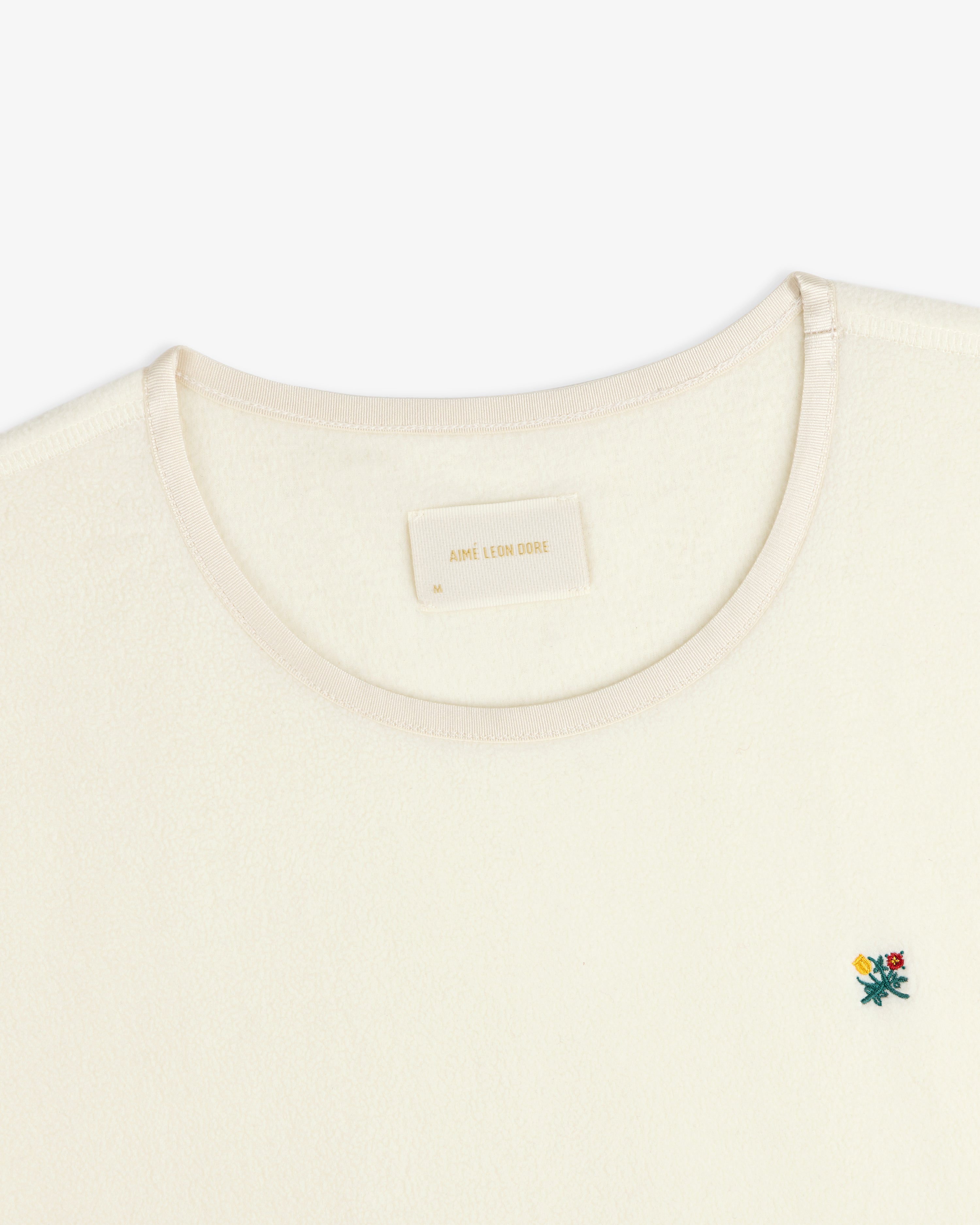 Crest Long-Sleeve Fleece Tee in cream with a small floral embroidery and an interior neck label.