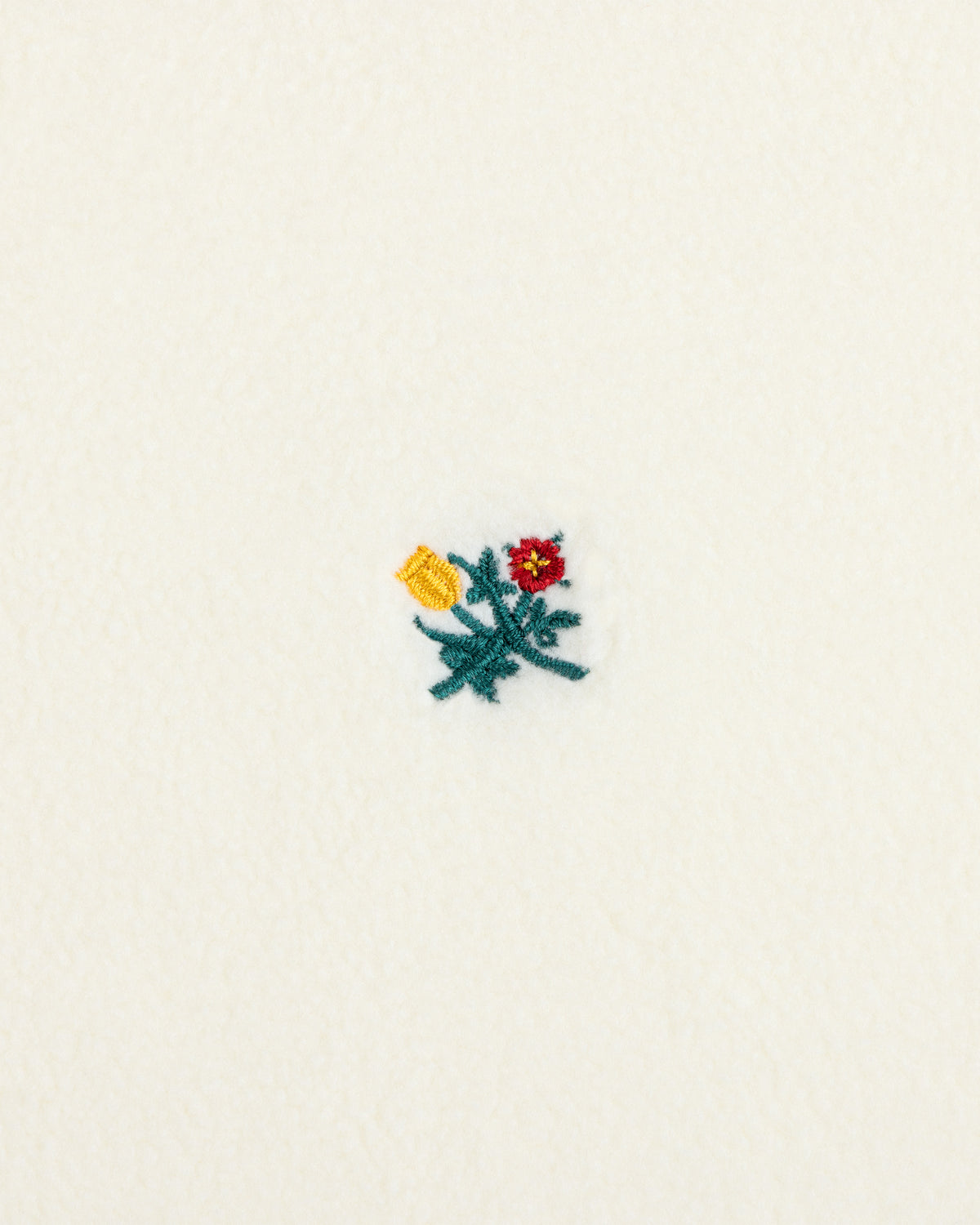 Crest Long-Sleeve Fleece Tee in cream-colored fleece with a small red, yellow, and green embroidered floral design.