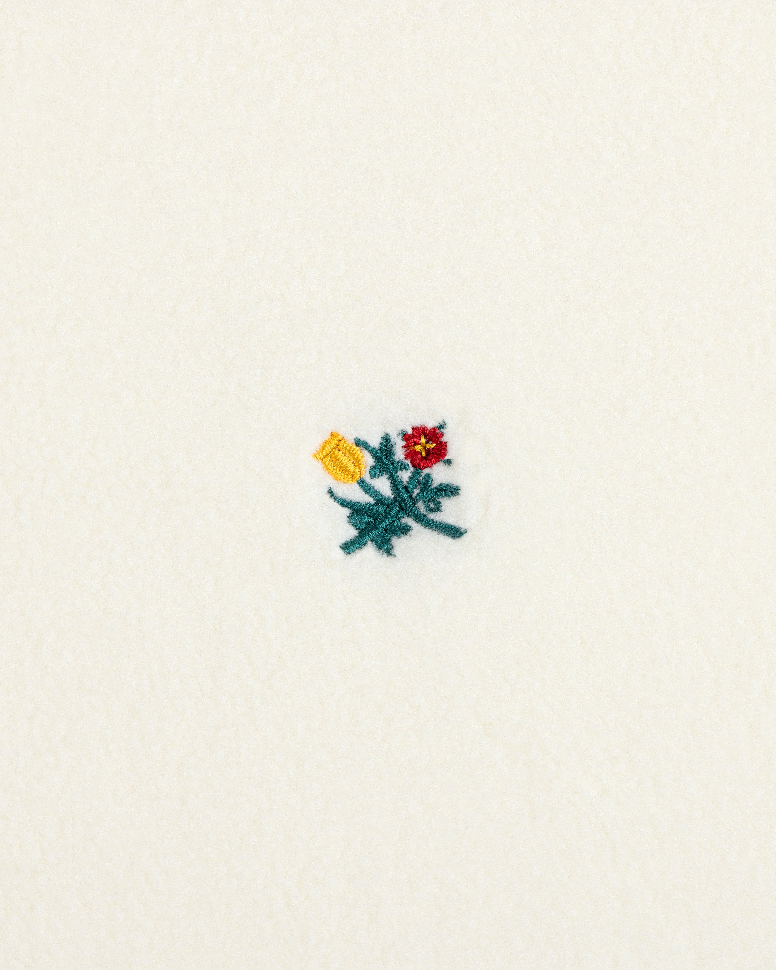 Crest Long-Sleeve Fleece Tee in cream-colored fleece with a small red, yellow, and green embroidered floral design.