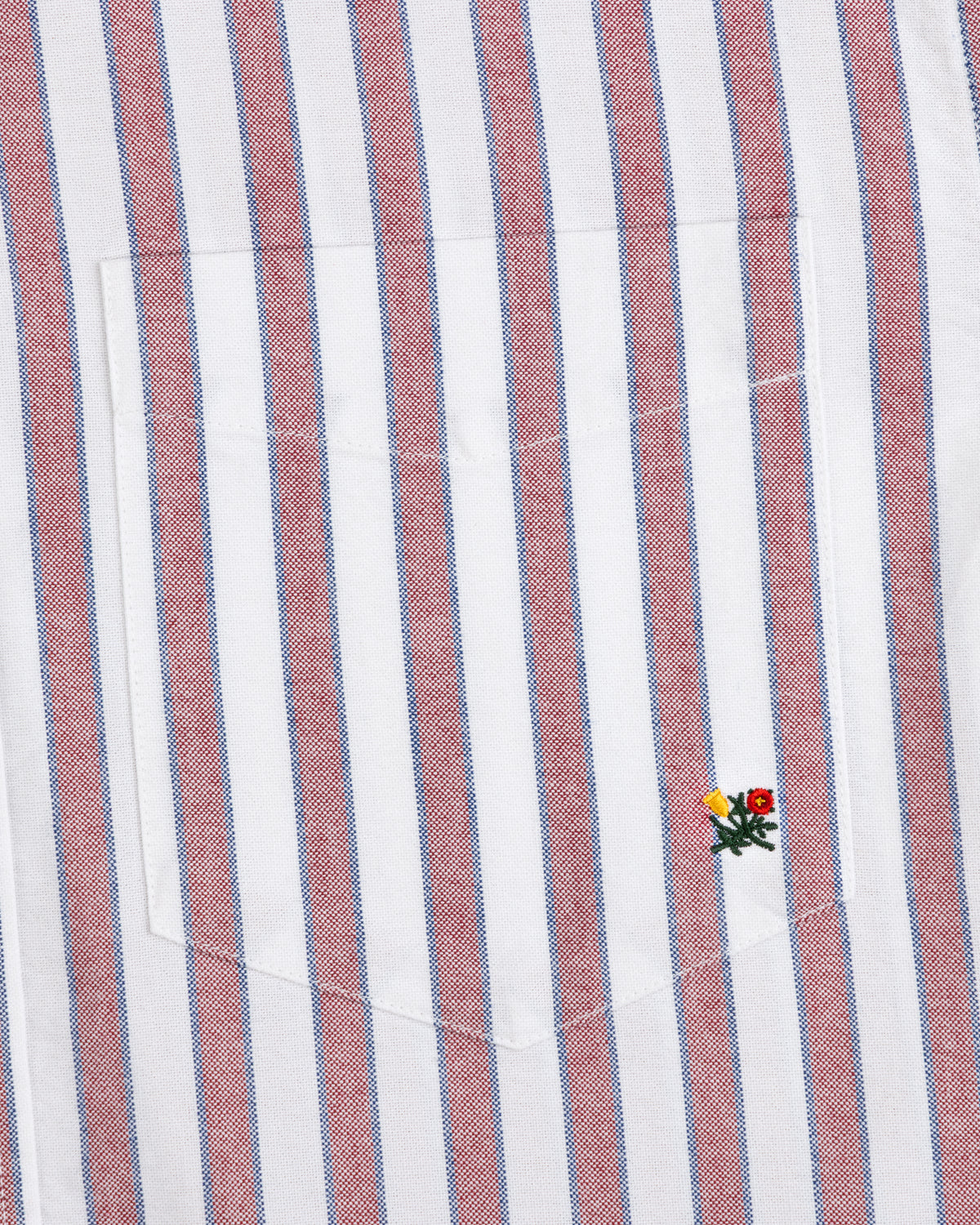 Striped Crest Oxford Shirt: white with red/blue stripes, chest pocket, and small yellow/red flower embroidery.