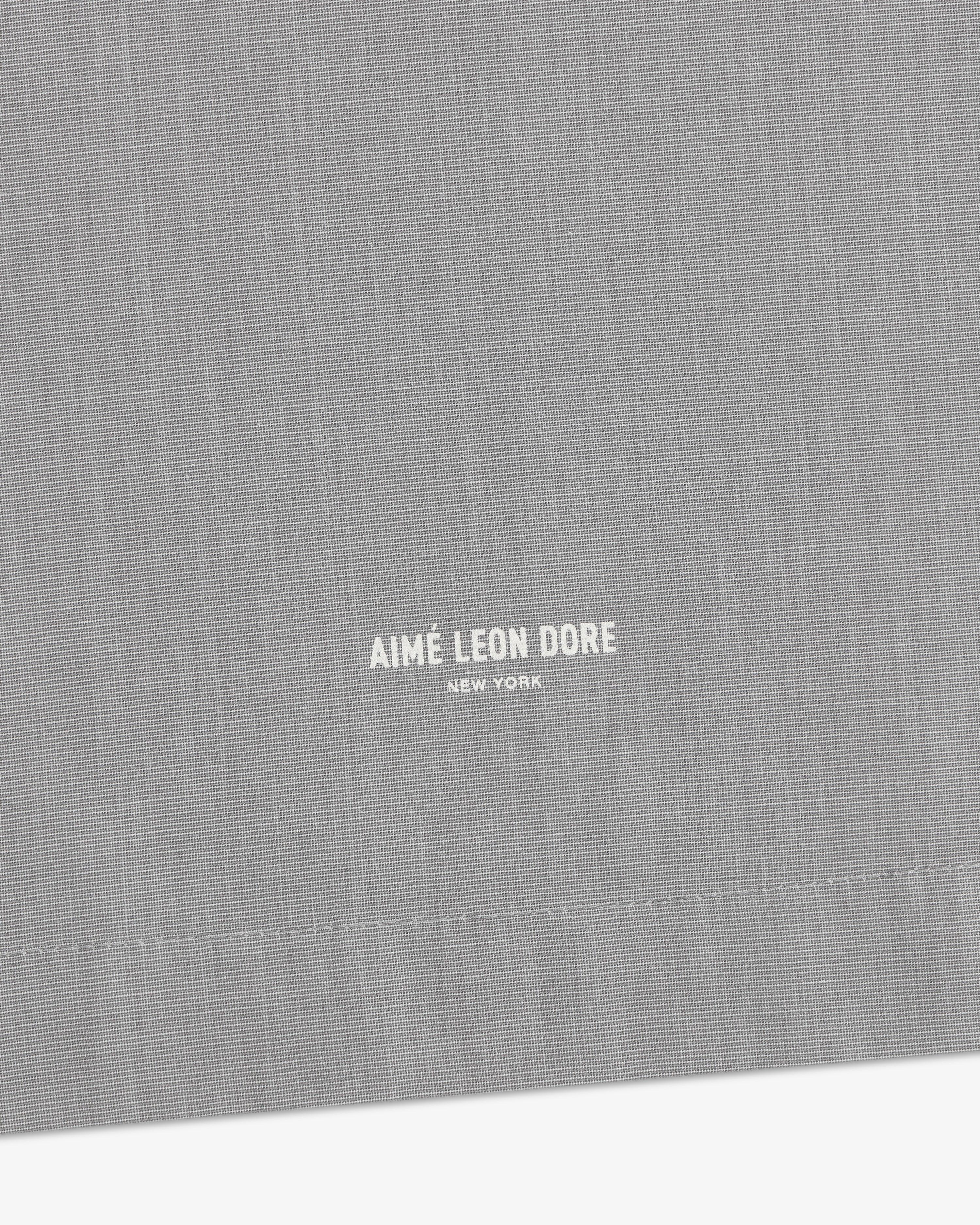 Gray Poplin Casual Shirt with small white Aimé Leon Dore New York text near the stitched hem.
