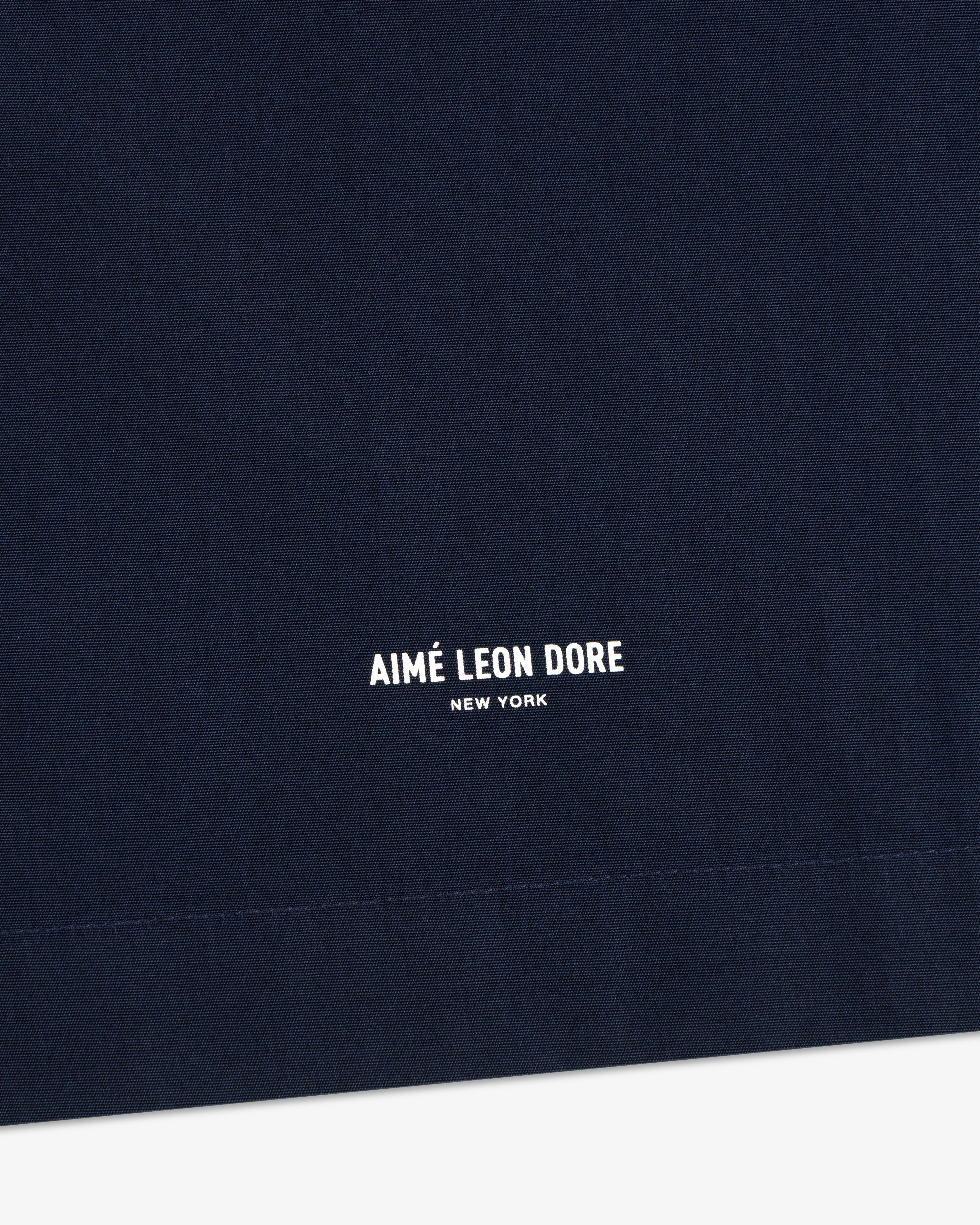 Close-up of navy Poplin Casual Shirt with AIMÉ LEON DORE NEW YORK in small white print near the bottom.