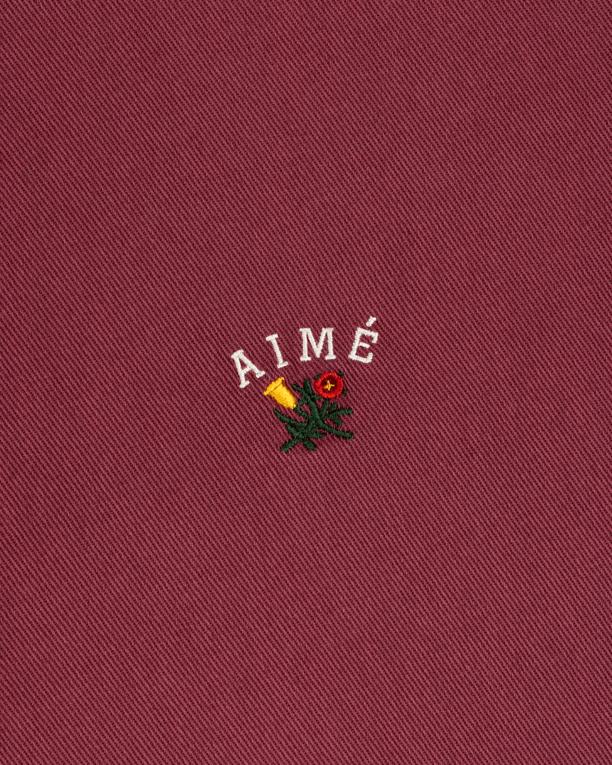 Garment Dyed Leon Overshirt in red with “AIMÉ” above an embroidered rose and candle.
