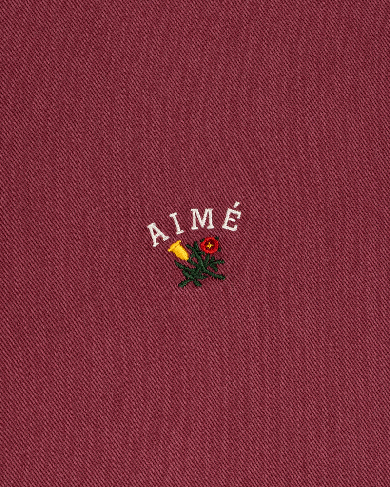 Garment Dyed Leon Overshirt in red with “AIMÉ” above an embroidered rose and candle.