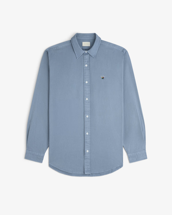 Garment Dyed Leon Overshirt in light blue with long sleeves and chest logo, shown on a white background.