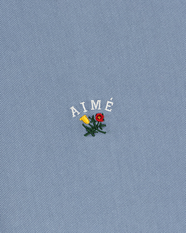 White AIMÉ embroidery and flower on blue textured fabric of the Garment Dyed Leon Overshirt.