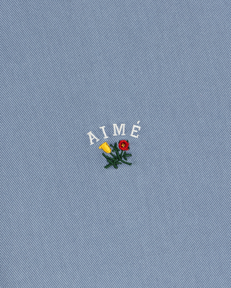 White AIMÉ embroidery and flower on blue textured fabric of the Garment Dyed Leon Overshirt.