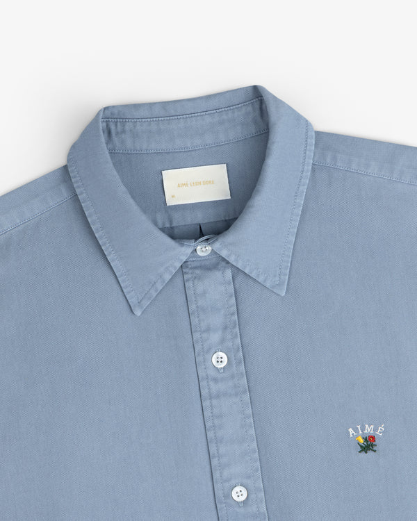 Garment Dyed Leon Overshirt in light blue with collar and small embroidered chest logo.