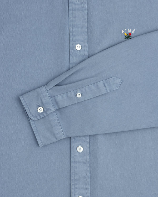 Garment Dyed Leon Overshirt: Light blue, white buttons, AIMÉ logo with flower on chest.