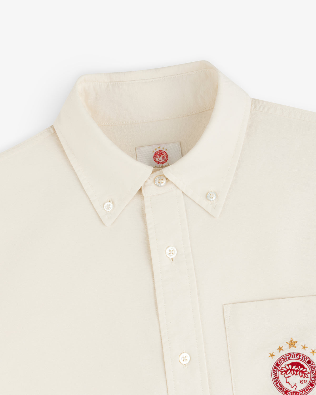 Cream-colored ALD / Olympiacos F.C. Logo Oxford Shirt with embroidered logos on the chest pocket and inner neck label.