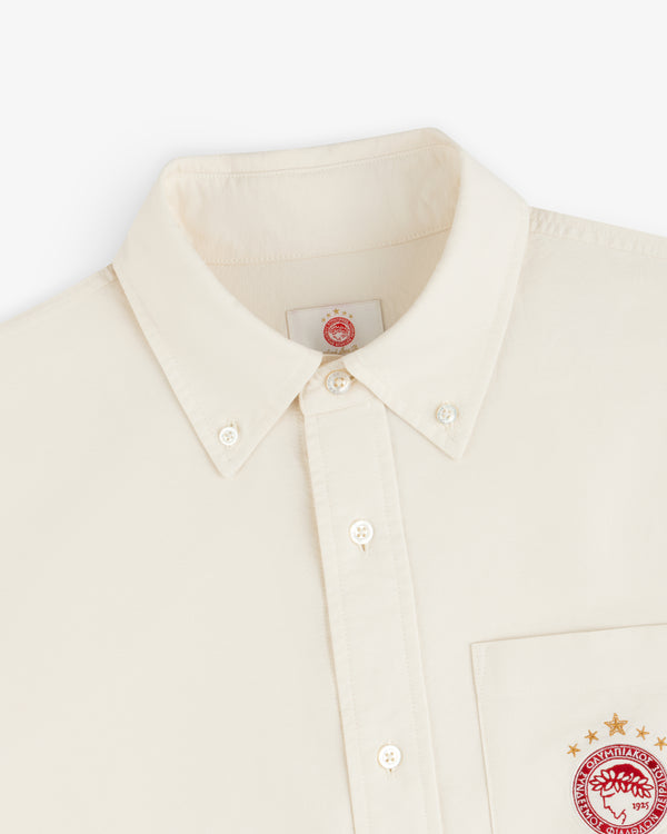 Cream-colored ALD / Olympiacos F.C. Logo Oxford Shirt with embroidered logos on the chest pocket and inner neck label.