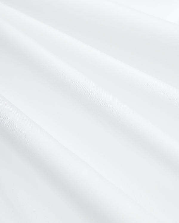 Close-up of folds in the white cotton fabric of a Button Down Poplin Shirt.