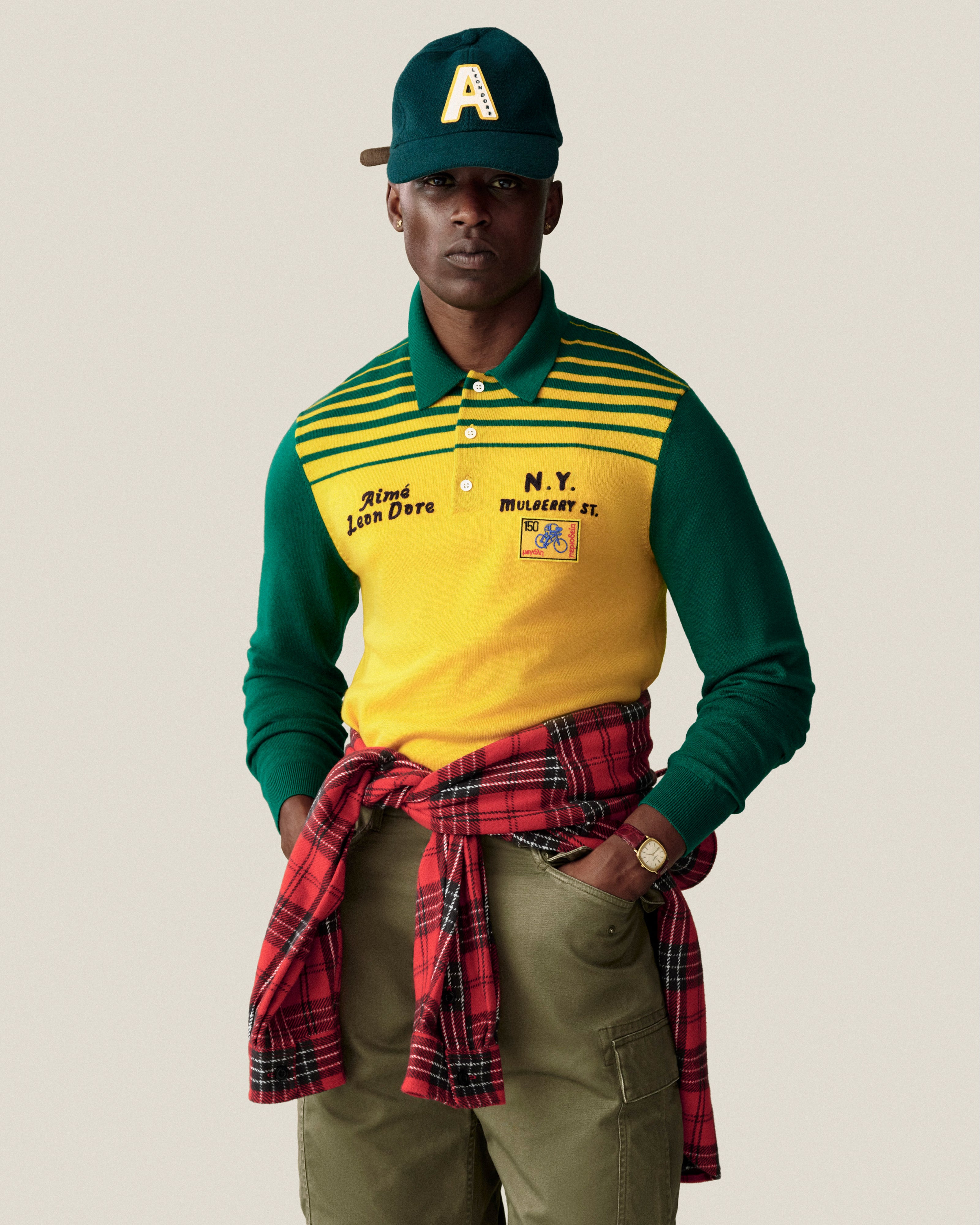 A man wears a dark green Wool Varsity Logo Hat with a yellow A, a yellow and green long-sleeve polo, and green cargo pants.