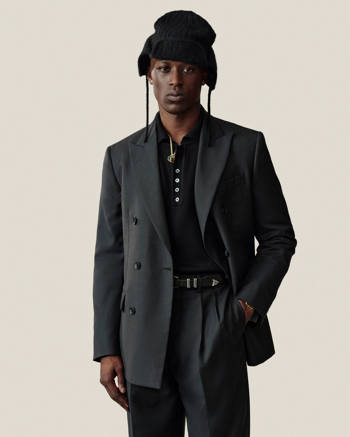 A man wearing a black Alpaca Wool Knit Earflap Hat, blazer, and polo shirt.