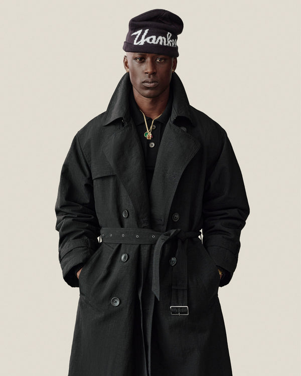 Man wears Double Breasted Nylon Trench Coat and beanie, “Thank You” text, hands in pockets, neutral background.