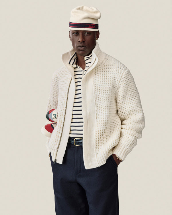A man in a Striped Crest Quarter Zip and beret holds rugby balls under his arm.