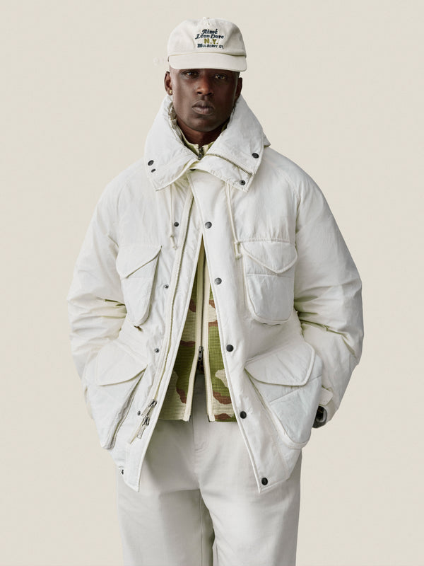 Man in a Mulberry Chainstitch Hat, white puffer jacket, and white pants against a plain light background.